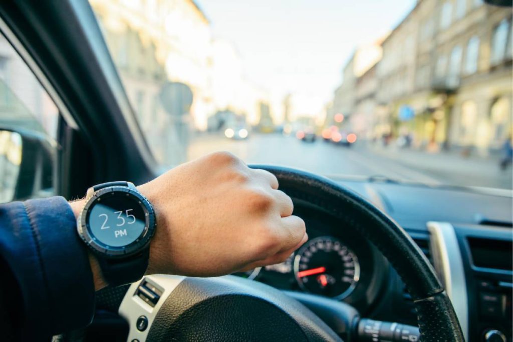 Un homme portant une montre dans sa voiture avec une assurance auto temporaire un jour